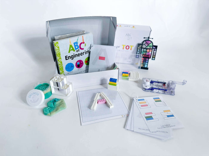 STEM-focused play and learn kit for kids aged 3-6. Includes a battery-free snap circuit, Lego playdough cutter with homemade playdough, straw STEM activity, Robot Suncatcher, Lego pieces, Lego educational cards, and 'The ABC's of Engineering' board book. Comes with a brochure containing additional activities and instructions.