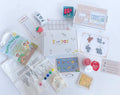 Kids' Farmer's Market play and learn kit with strawberry playdough, custom cutter, market signs, play money with a money poem, pretend cash register, and a canvas tote bag with paint. Ideal for imaginative play and learning about money.