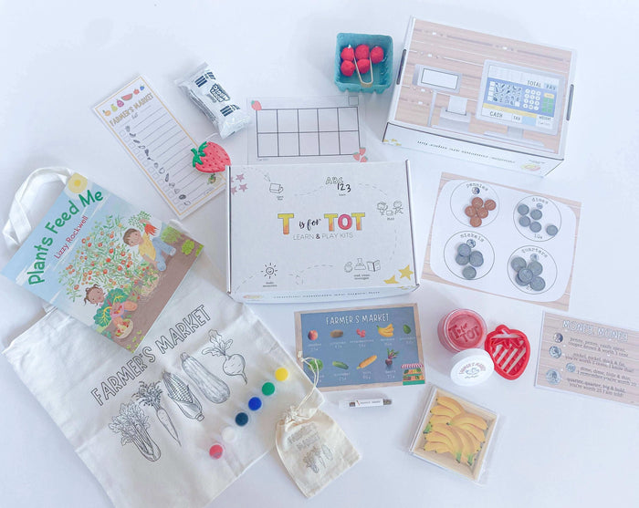 Kids' Farmer's Market play and learn kit with strawberry playdough, custom cutter, market signs, play money with a money poem, pretend cash register, and a canvas tote bag with paint. Ideal for imaginative play and learning about money.