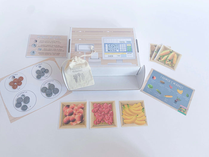 Children's Farmer's Market kit with strawberry-scented playdough, custom cutter, canvas tote bag for painting, pretend cash register, and play money with a money poem to learn coin values. Comes with 'Plants Feed Me' book and tens frame math activity.