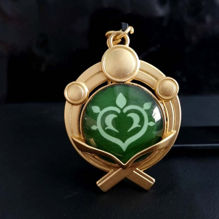 Genshin Impact Inazuma Vision Keychain: gold, teal stylized winged or floral emblem, ornamental fantasy-inspired style