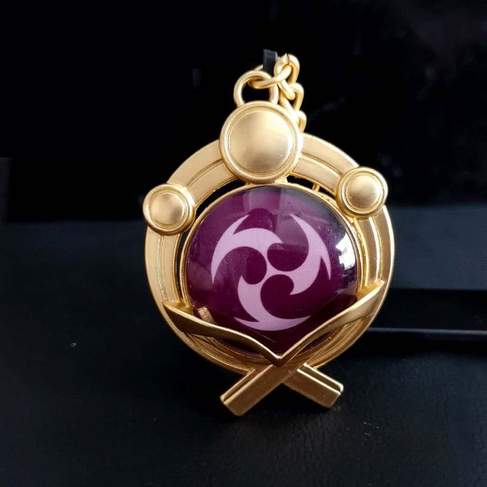 Genshin Impact Inazuma Vision Keychain: gold, teal stylized winged or floral emblem, ornamental fantasy-inspired style