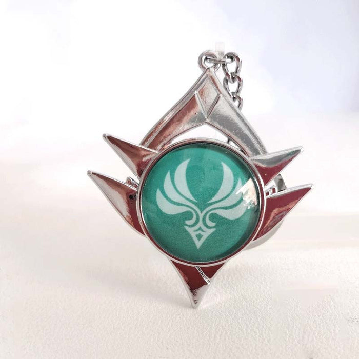 Genshin Impact Snezhnaya Vision Keychain: silver, teal green stylized emblem/symbol, fantasy emblem style