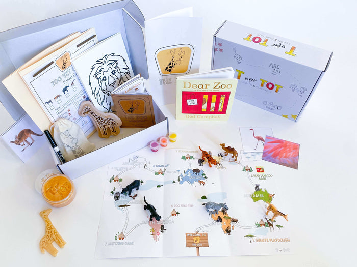Ages 3-6. Zoo-themed play and learn kit for kids with giraffe playdough cutter, homemade playdough, zoo map, vet folder with expo marker, play animals, and 'Going to the Zoo' book. Includes zoo sketch journal, scavenger hunt, animal matching game, and ot