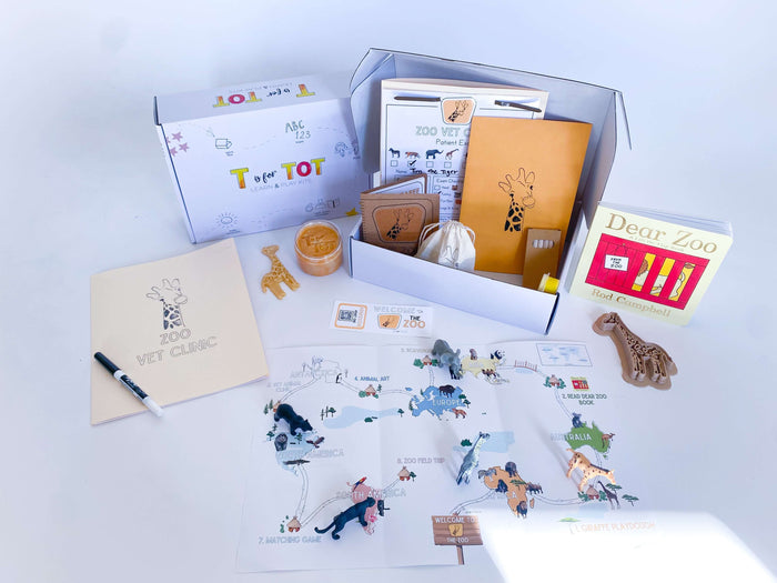 Interactive zoo-themed kit for children with a giraffe playdough cutter, homemade playdough, zoo map, and a vet folder with expo marker for pretend play. Includes play animals, 'Going to the Zoo' book, and scavenger hunt for learning and fun.