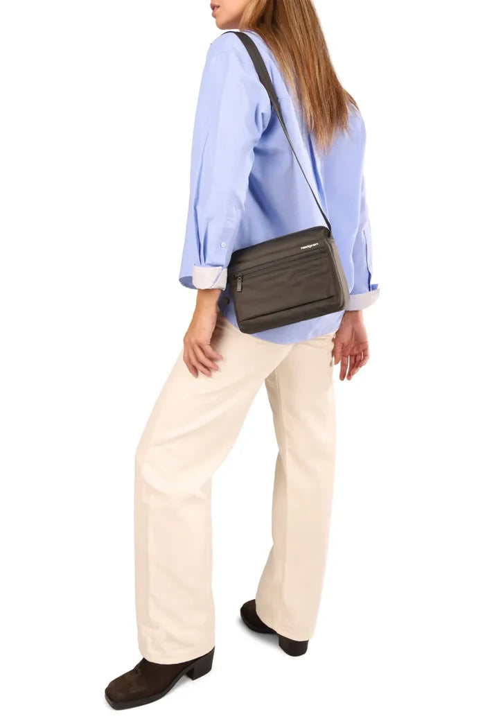 Hedgren EYE NEO Crossbody Bag with RFID Pocket in Maroon Banner, worn crossbody at the waist over a blue shirt and cream trousers
