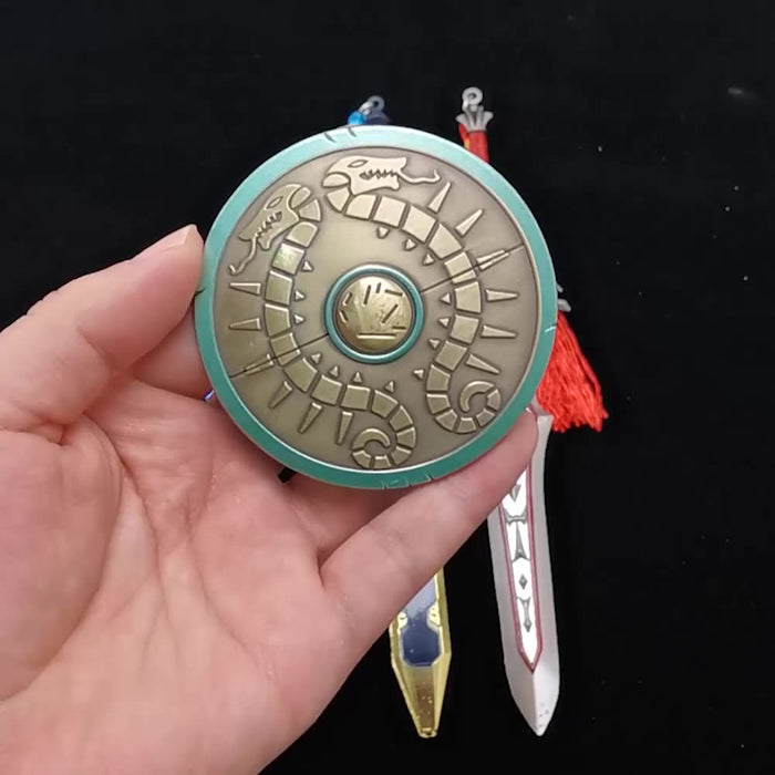 Legend of Zelda Traveler's Shield Metal Model: turquoise, gold centipede-like creature, stylized fantasy cartoon style